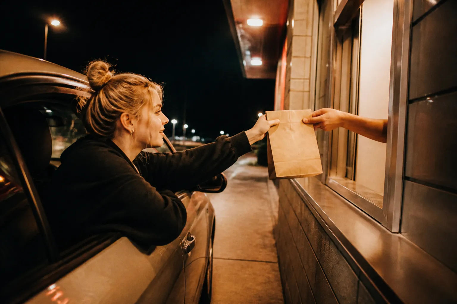 A fast food drive-thru lane glowing under lights at night