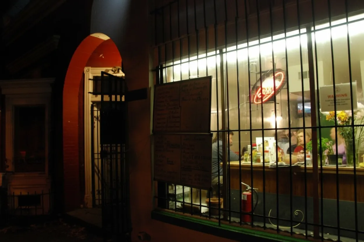 A warm neighborhood restaurant window glowing on a weeknight