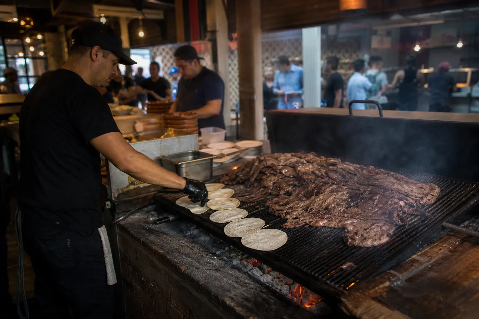 Handmade Sonoran flour tortillas grilling over a hot mesquite wood fire in a busy DTLA restaurant.