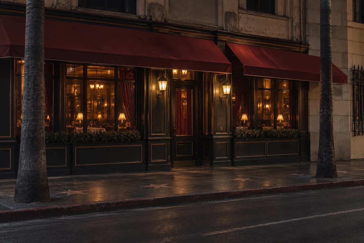Night photograph of a historic restaurant frontage on Hollywood Boulevard, with warm amber light behind dark windows, deep red details and a calm street outside.