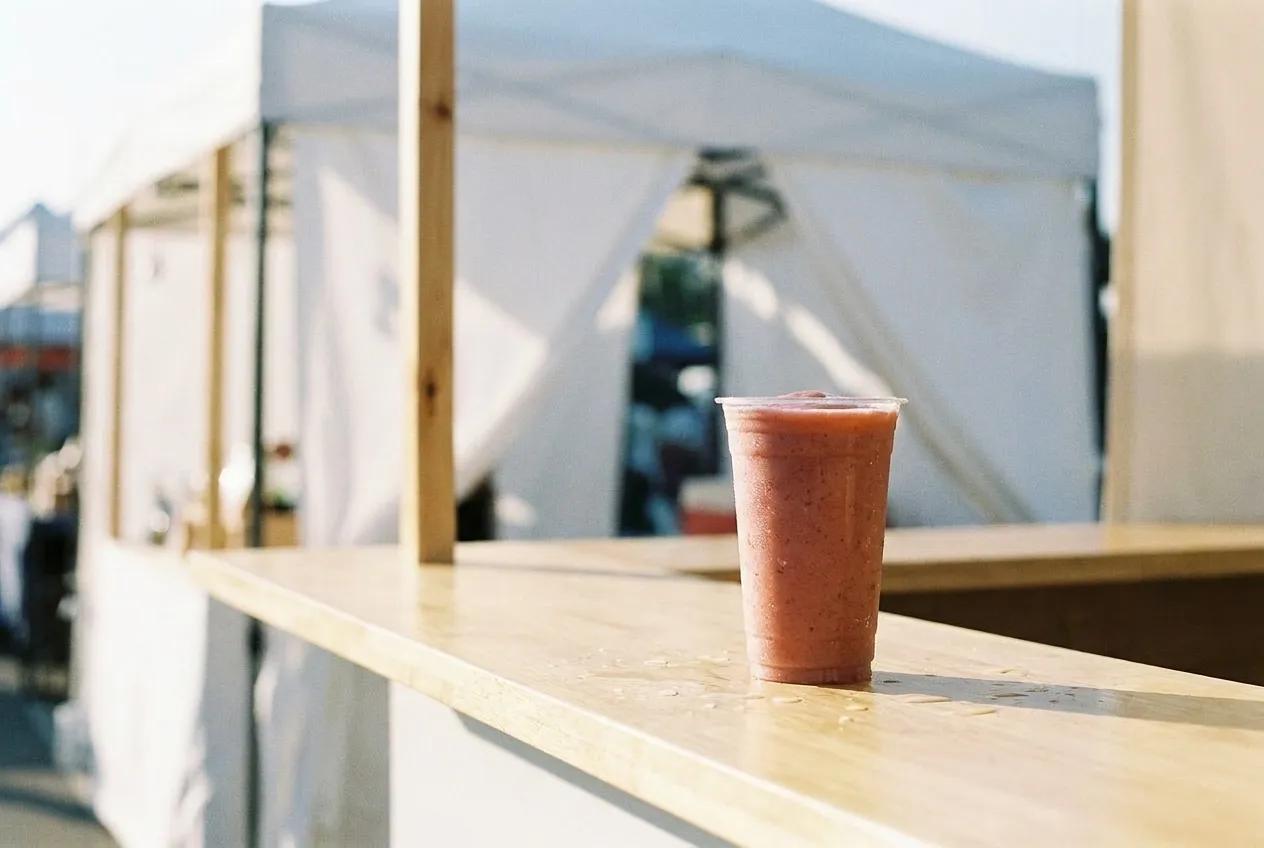Bright pink smoothie in a clear plastic cup on a marble counter inside an Erewhon market.