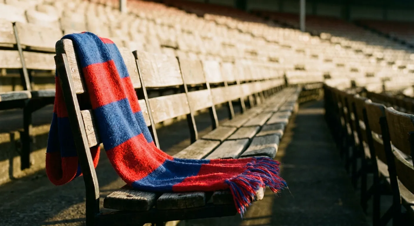 A lone red and blue scarf draped on a stadium seat with soft morning light across empty rows