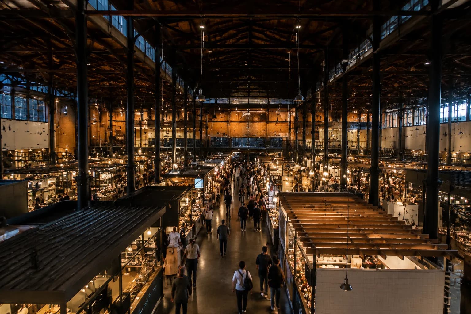 Interior of Grand Central Market in downtown Los Angeles at evening, with stalls lit and people walking through the arcade