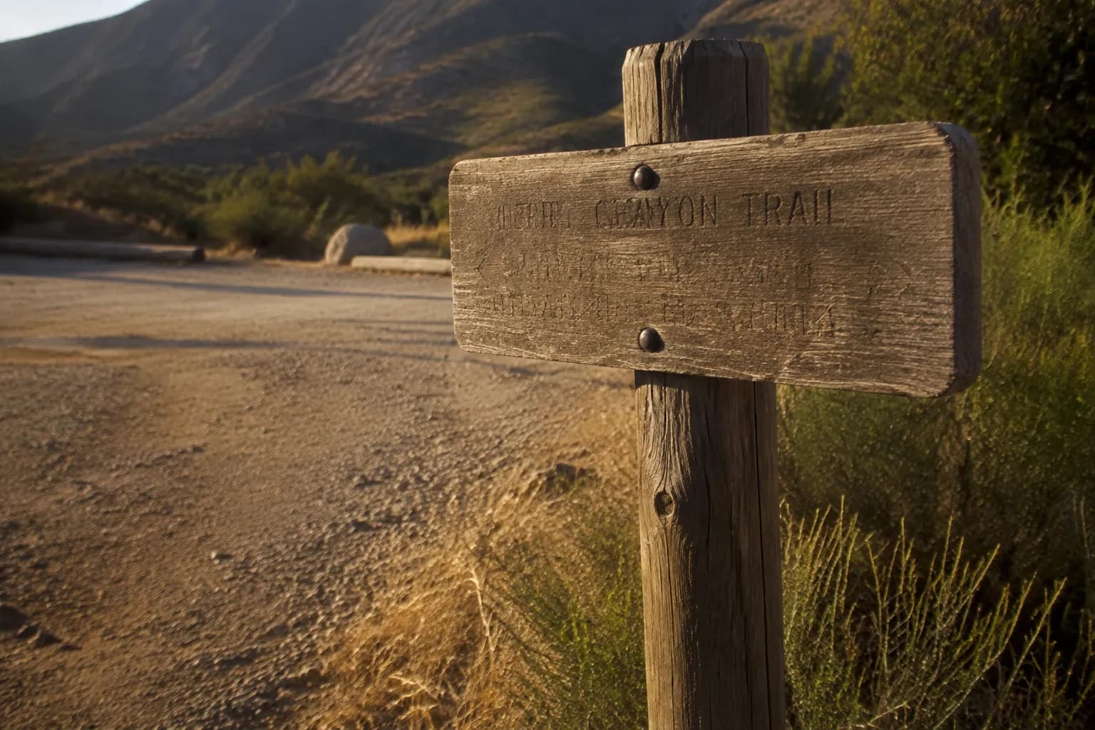 Trailhead sign and parking area at a Malibu canyon entrance in late afternoon light