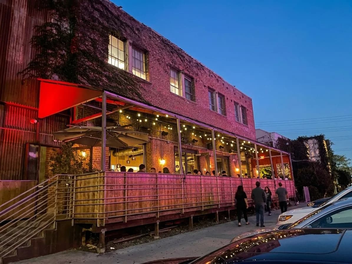 Arts District restaurant exterior at dusk with warm windows and passing cars
