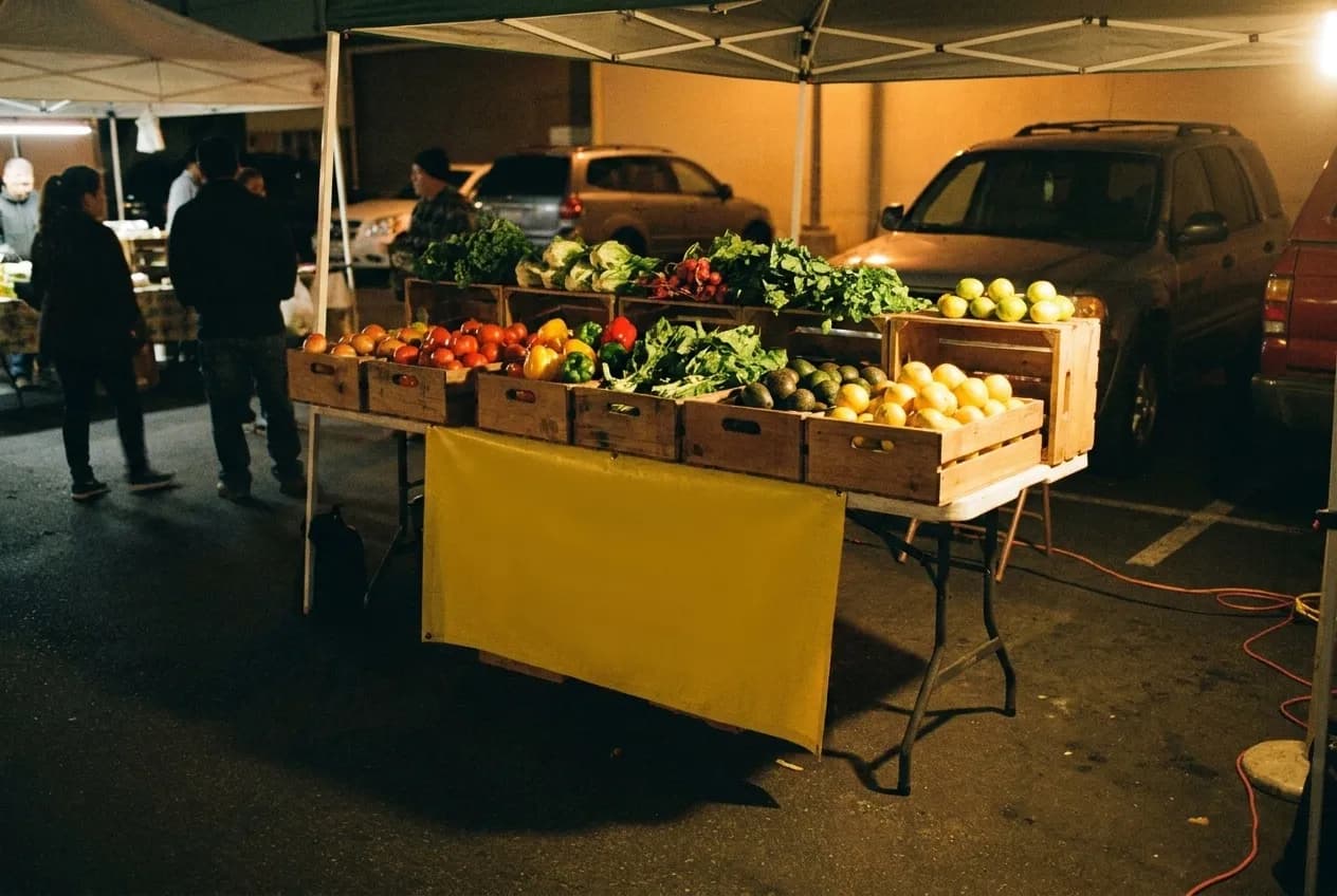 Crates of produce at a neighbourhood market stall under working lights