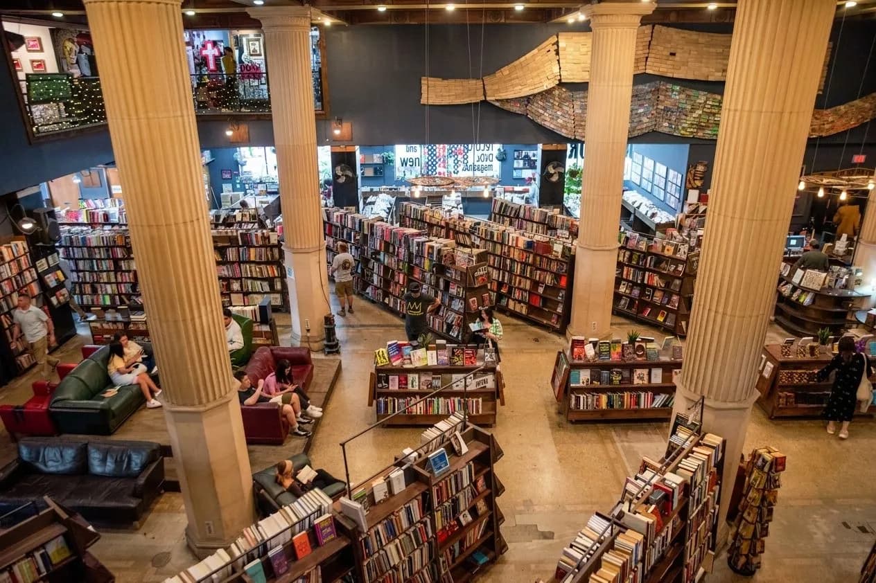 Wide interior view of a historic downtown bookstore with tall shelves and browsing readers