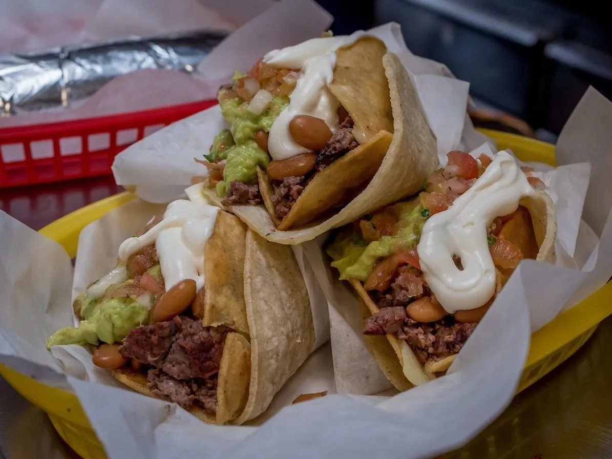 Tacos on a paper tray with salsa and lime in a Mission taqueria