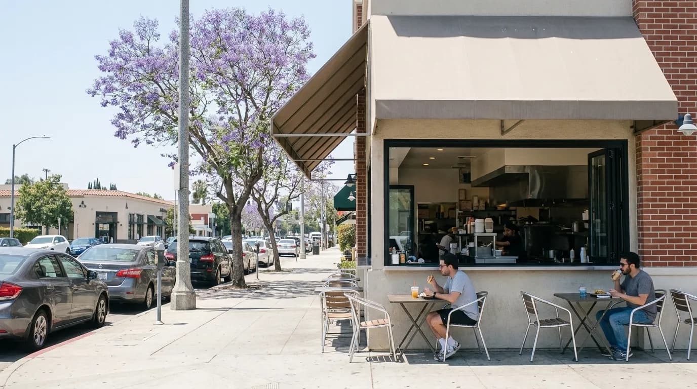 A small daytime counter restaurant on a Los Angeles boulevard with a few patio tables shaded by an awning.