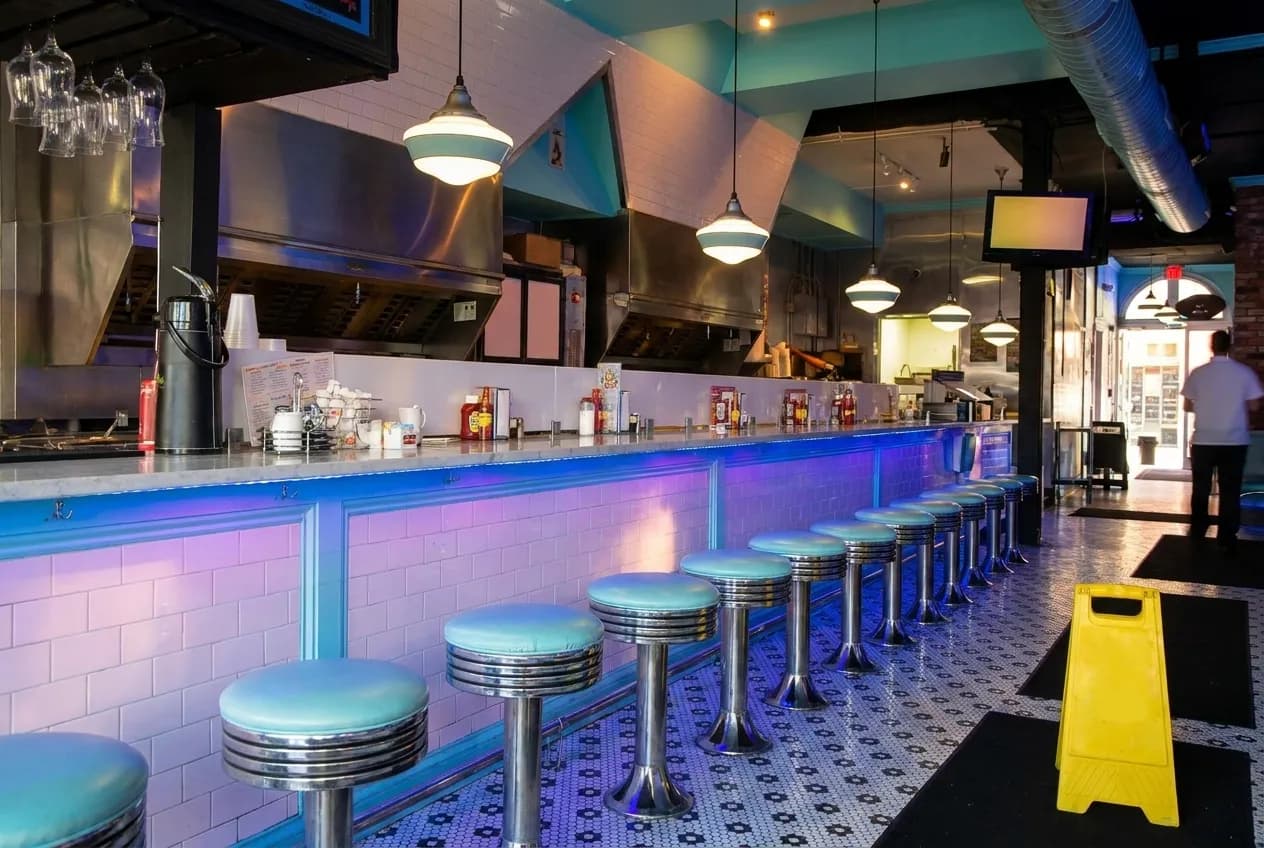An empty counter with stools in a row, waiting for a quiet service