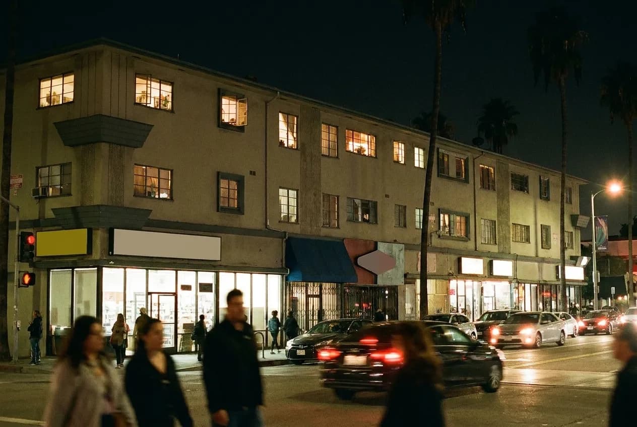 A dense mid-city block at night, upper-floor windows lit above a busy street
