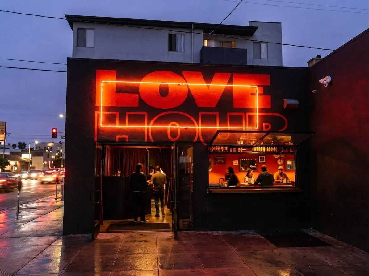 A neon-lit burger spot exterior on a busy Los Angeles street at dusk