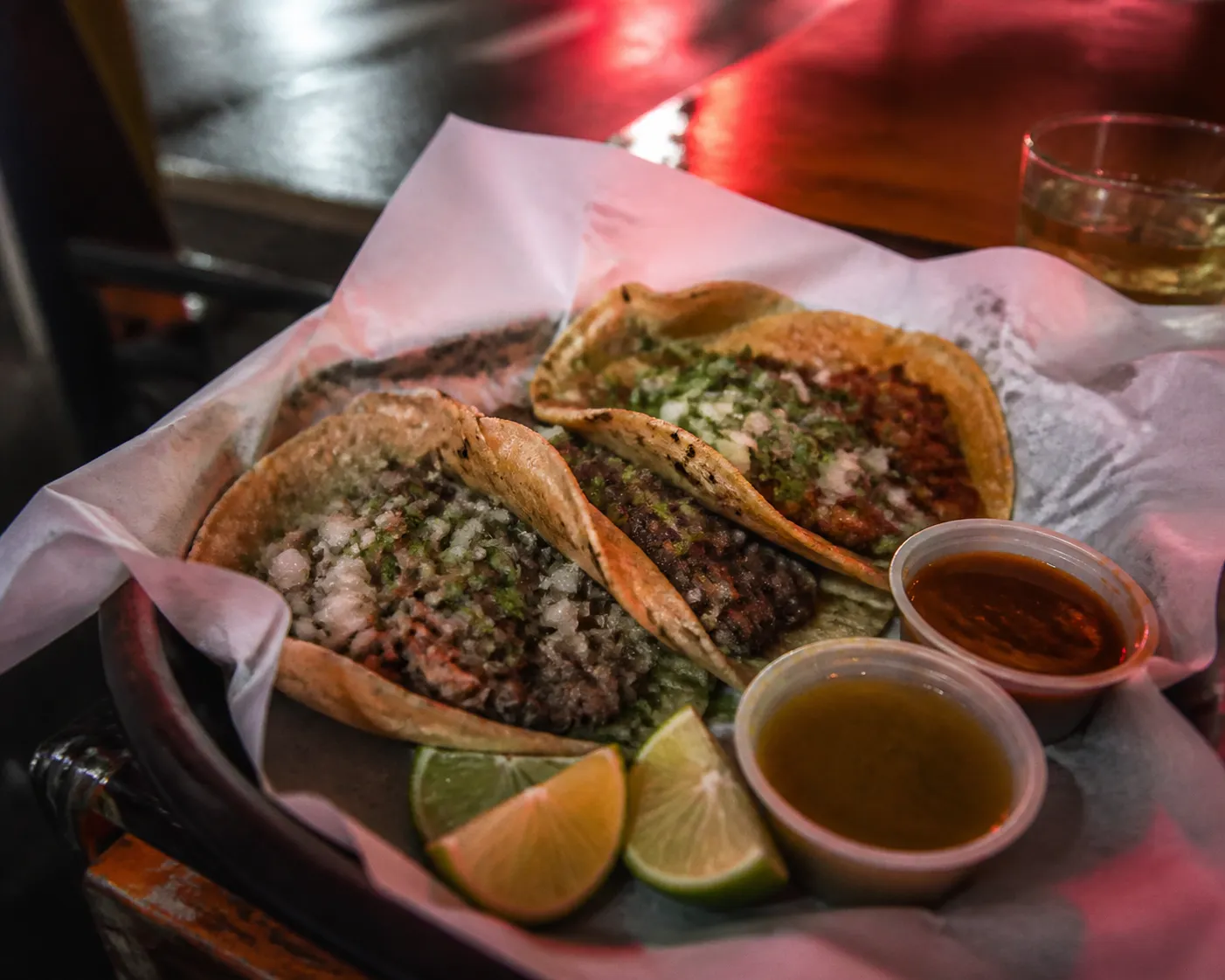 Late-night tacos on a tray with salsa and lime on a sidewalk table