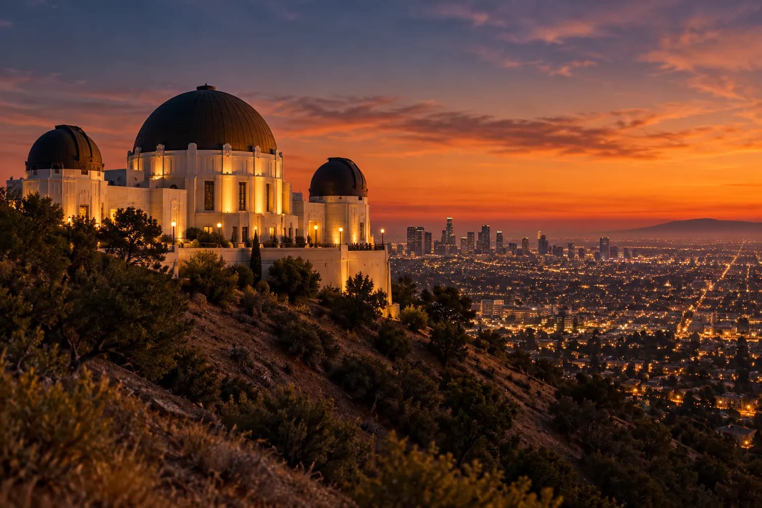 A domed observatory building on a hillside above a city at dusk