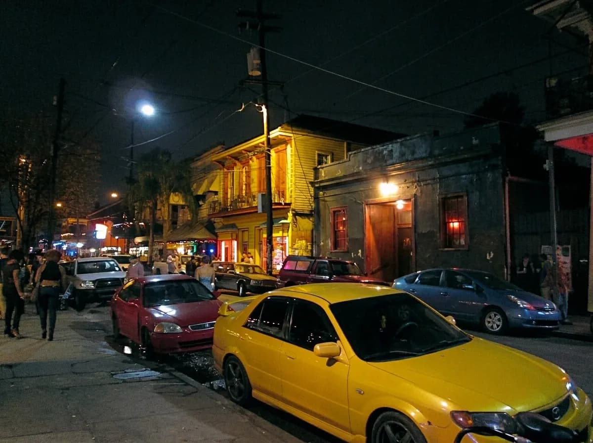 A small music venue front at night with a bare bulb over a recessed doorway and warm light escaping inside