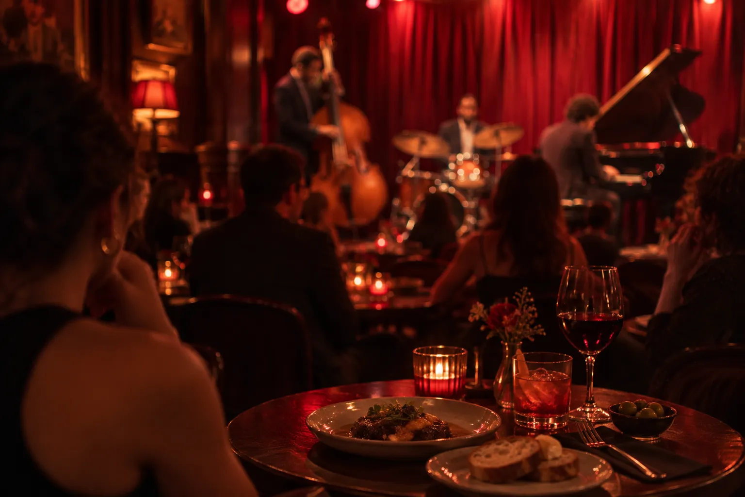 An intimate jazz club interior with closely packed tables facing a low stage and warm red lighting