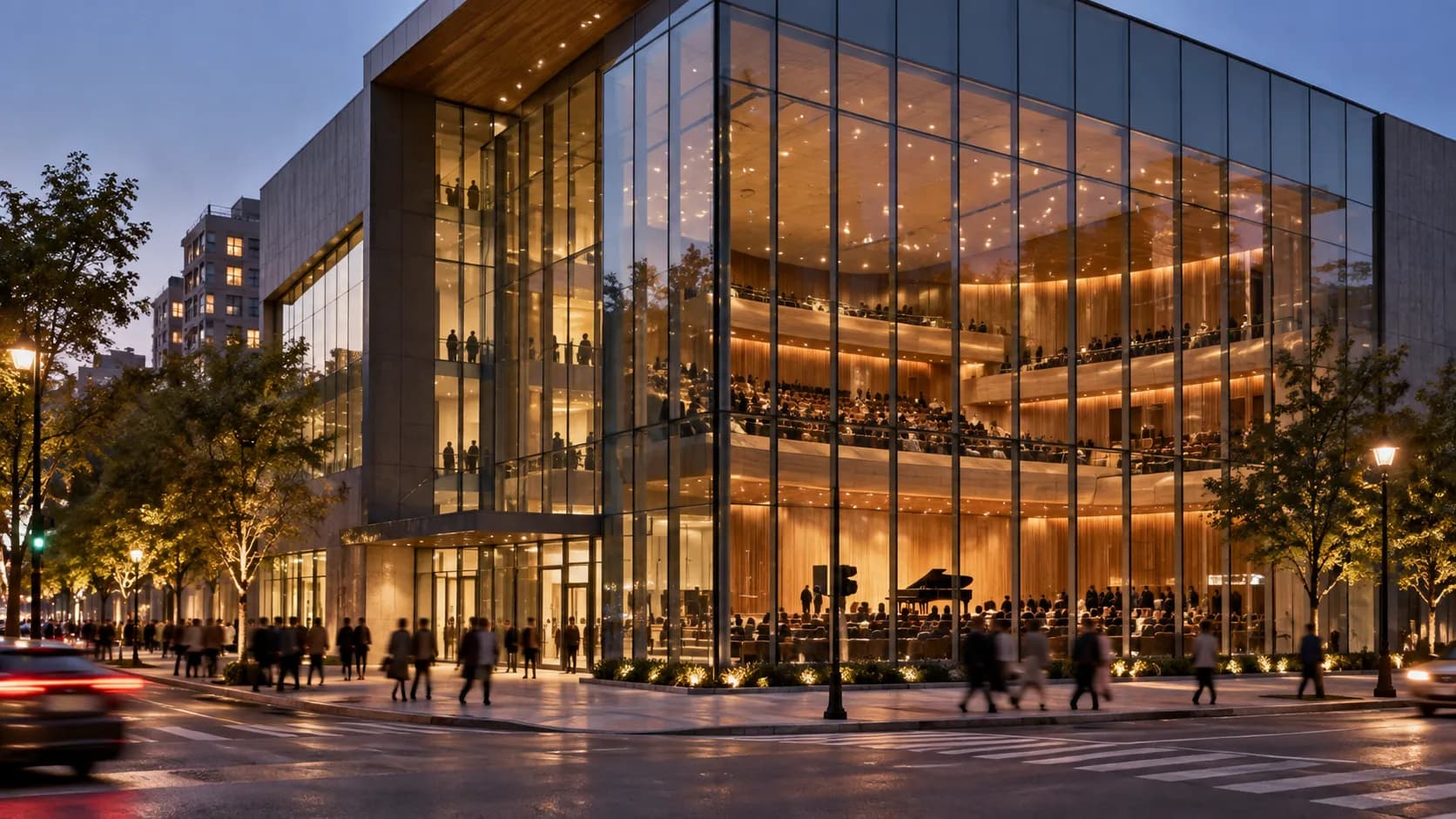 A modern glass-fronted concert hall building on a corner with tiered seating visible inside