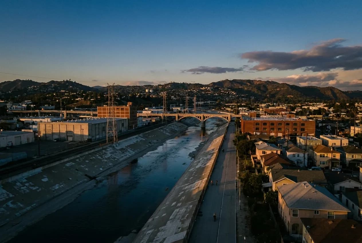 A concrete river channel at dusk with industrial buildings and a paved path