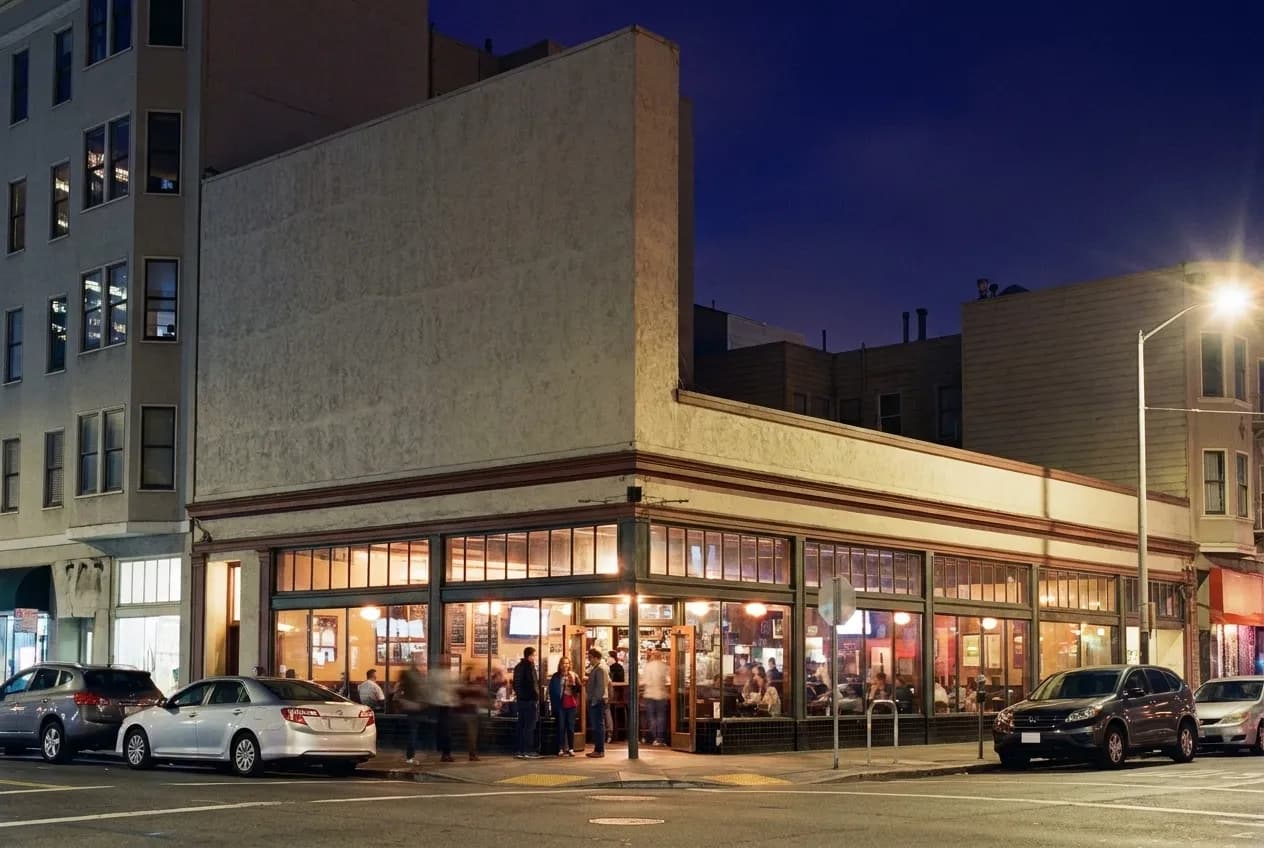 A neighbourhood commercial street in San Francisco at night with pub windows lit