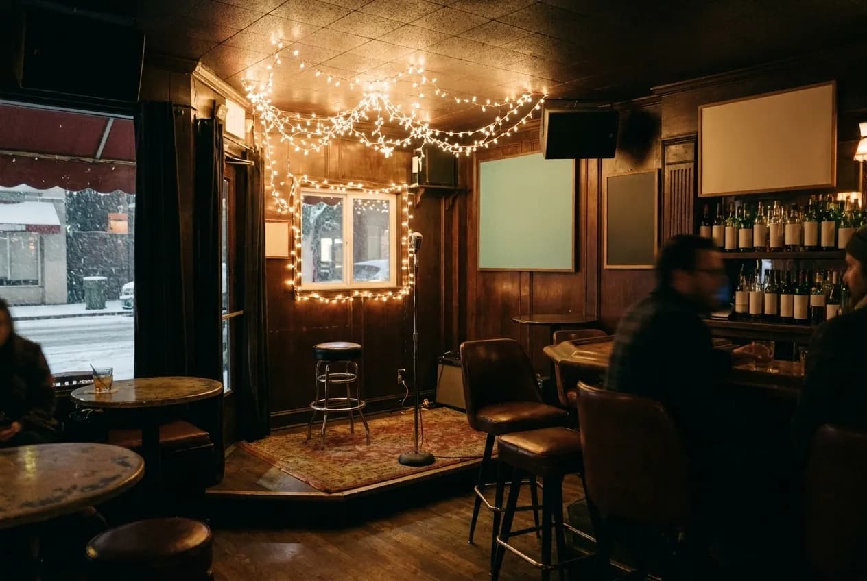 A dim neighbourhood bar interior with a small stage area and string lights in San Francisco