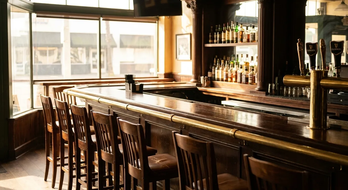 Dark wood bar counter at Auld Dubliner in Long Beach with whiskey bottles lining back shelves and Guinness taps visible in foreground