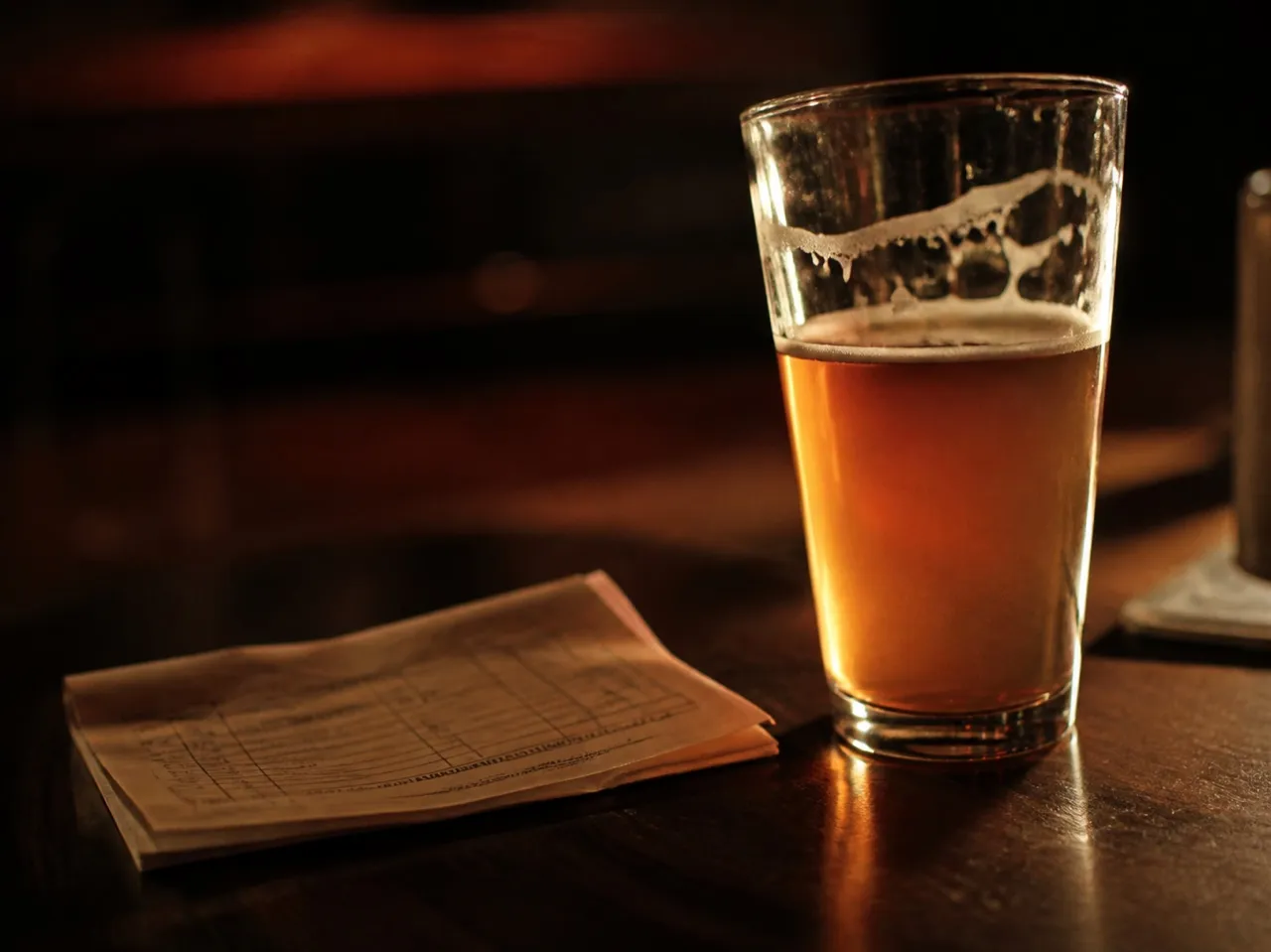 Pint glass and a folded fixture list on a bar table