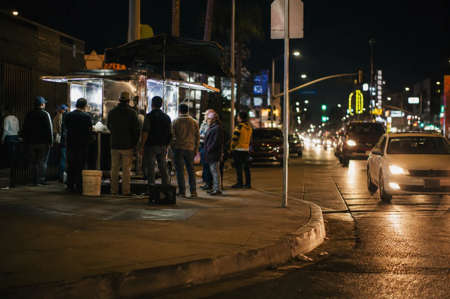Night street in Koreatown with a glowing taco stand and passing car lights
