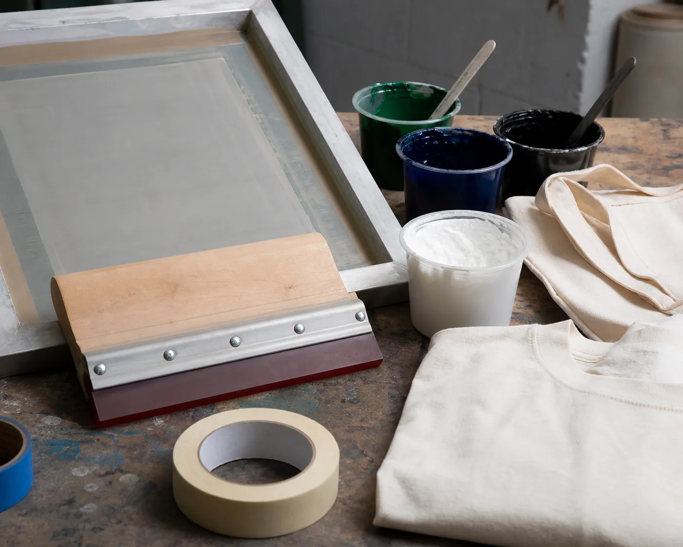 Screen printing tools, squeegee, ink, and blank tote on a worktable