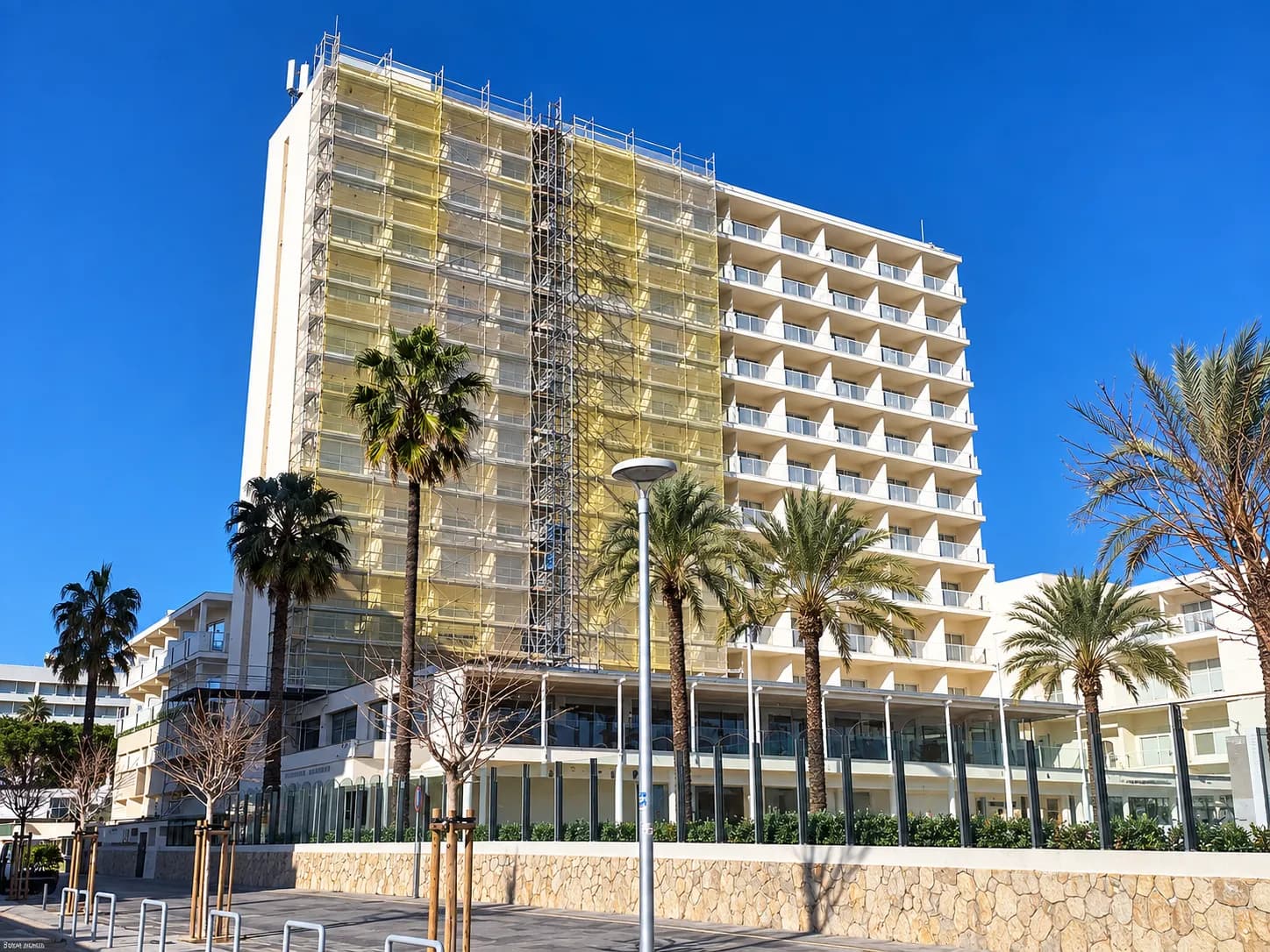 A hotel facade partly covered in scaffolding under a bright sky