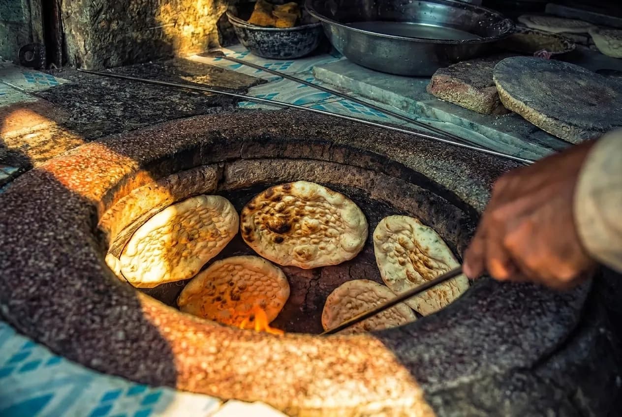 Flatbread puffing on the wall of a hot clay oven