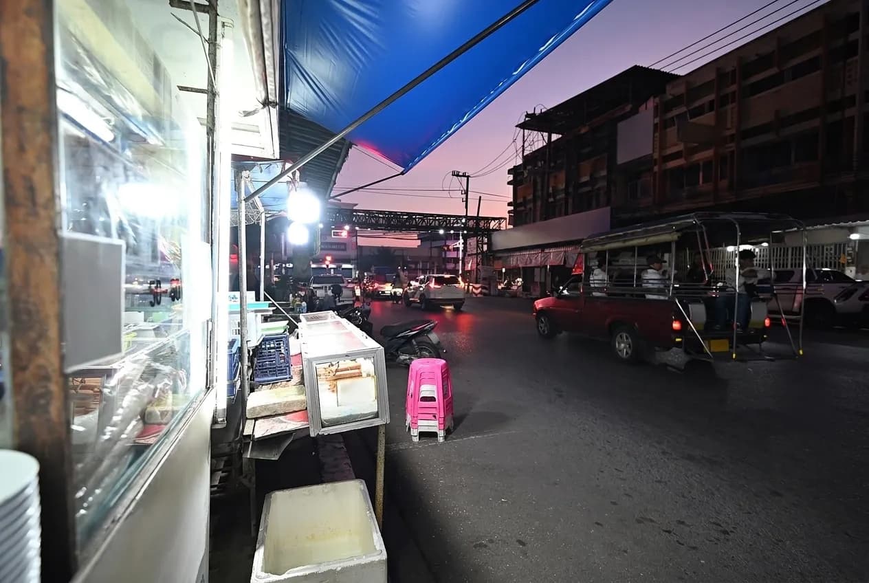 A commercial street of low buildings with awnings under a bright sky