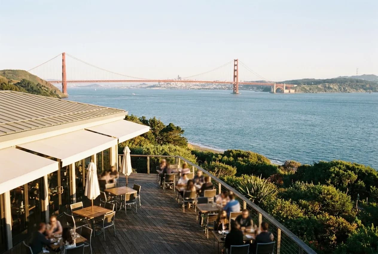 A restaurant terrace looking out over water toward a distant bridge in late afternoon