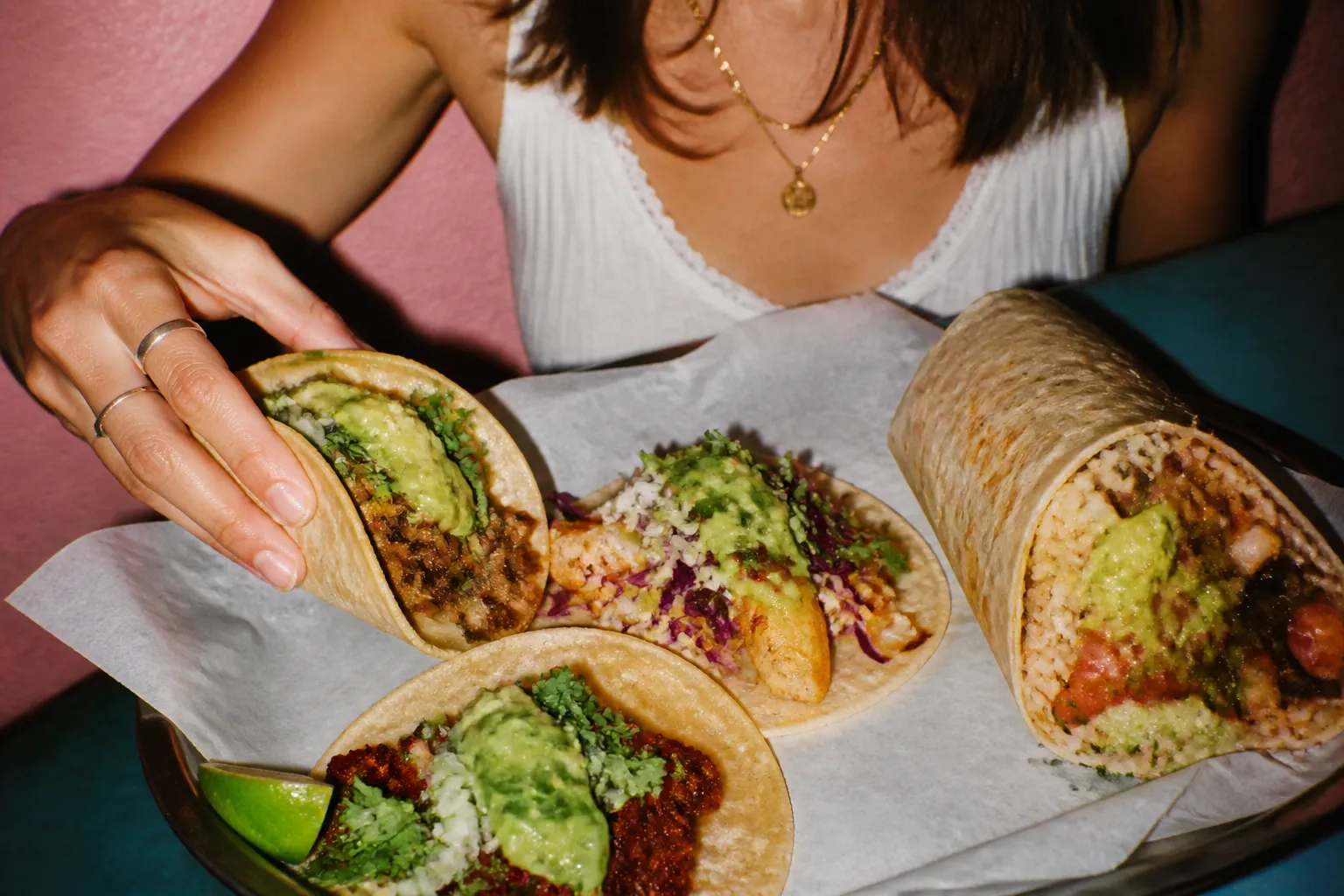 Colorful street tacos and a burrito on a paper-lined tray