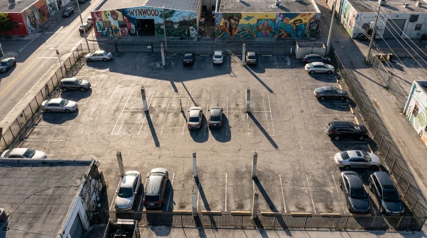 Public parking lot in Wynwood with cracked asphalt and warehouse murals in the background