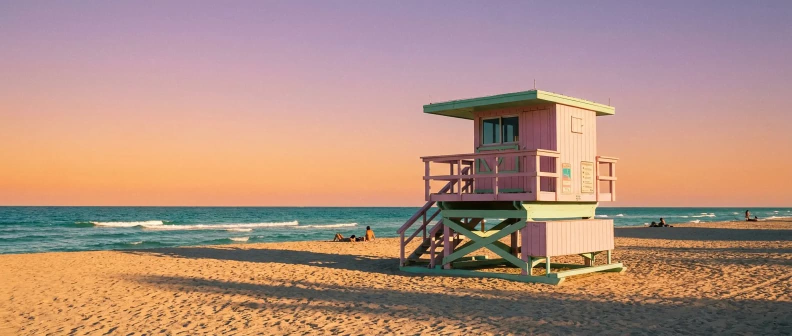 People relaxing on Miami Beach at golden hour with lifeguard tower and gentle surf
