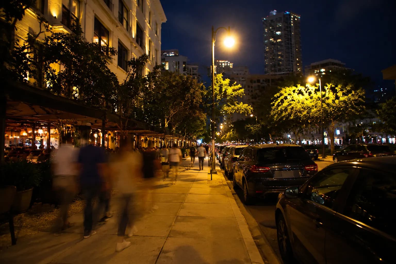 Night street scene in Commodore Plaza Coconut Grove with lit storefronts and pedestrians