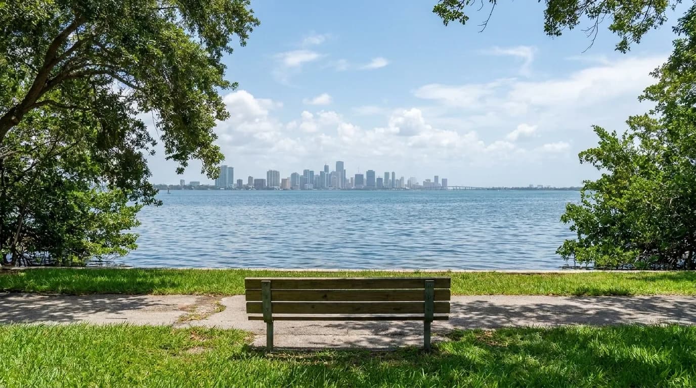 A peaceful bayside park in Coconut Grove offers water views and shaded benches with the Miami skyline in the distance.