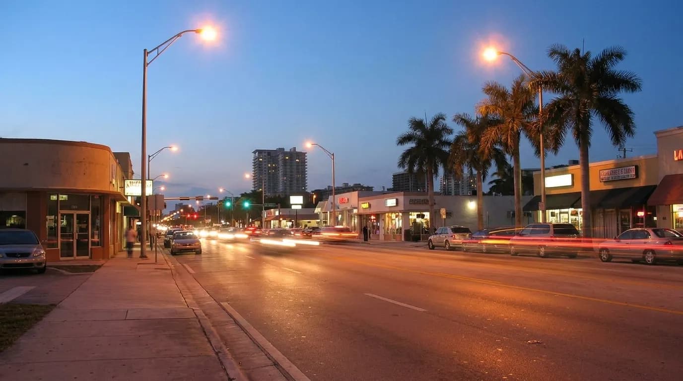 Evening traffic along a commercial strip in Miami with streetlights and storefronts