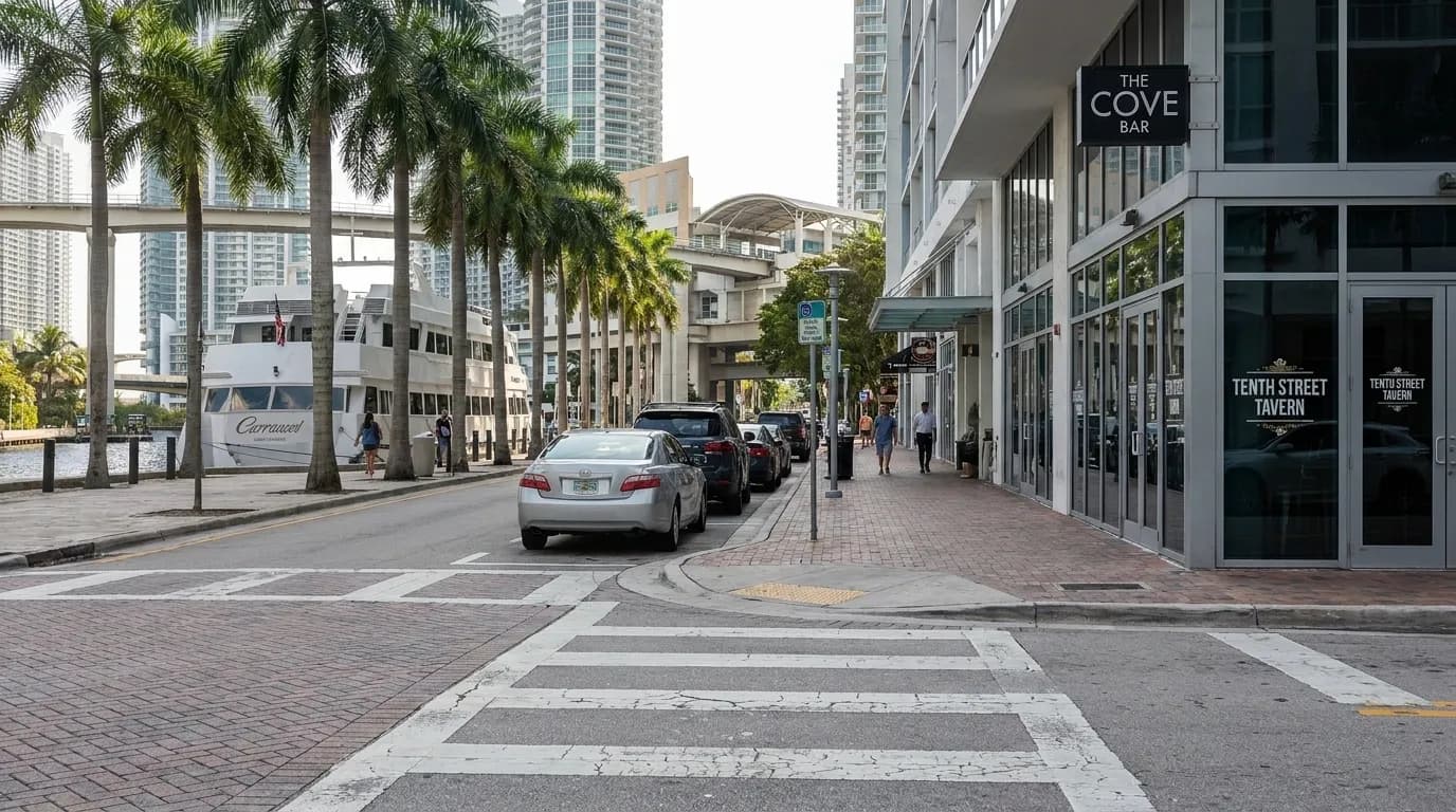 Brickell Avenue in Downtown Miami showing storefronts, parked cars, and Metromover station in the distance