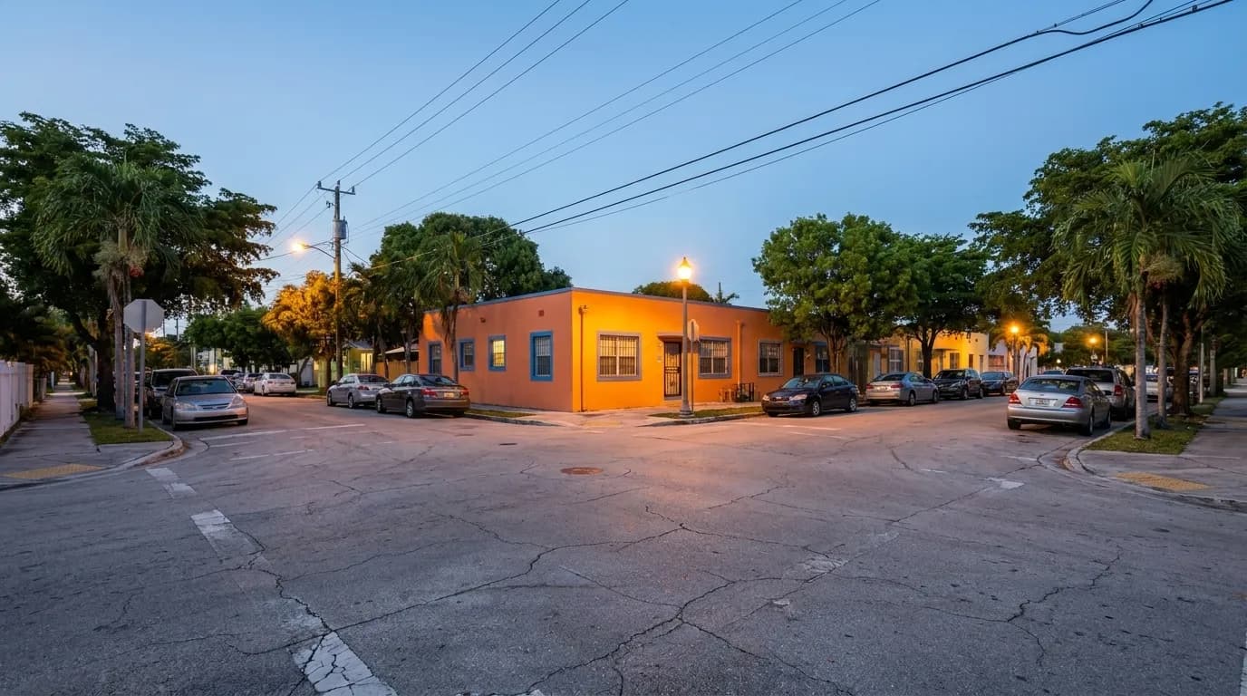 Quiet street in Little Haiti at dusk with colorful buildings and streetlights coming on