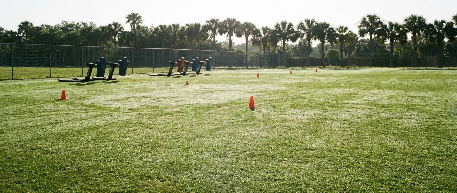Blocking sleds and cones on an empty football practice field under morning Florida sun