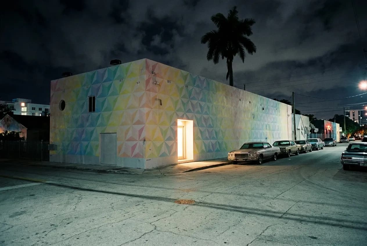 A painted warehouse facade on a Wynwood side street in Miami at night with warm light spilling from a doorway