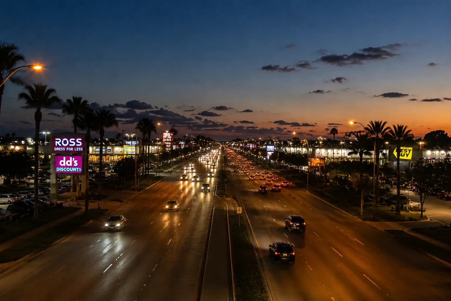 Biscayne Boulevard at dusk with traffic flowing past retail corridors in North Miami