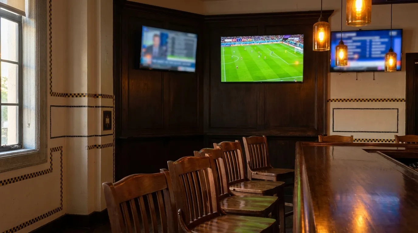 Interior of a Miami sports bar with multiple screens and empty bar stools in late afternoon light