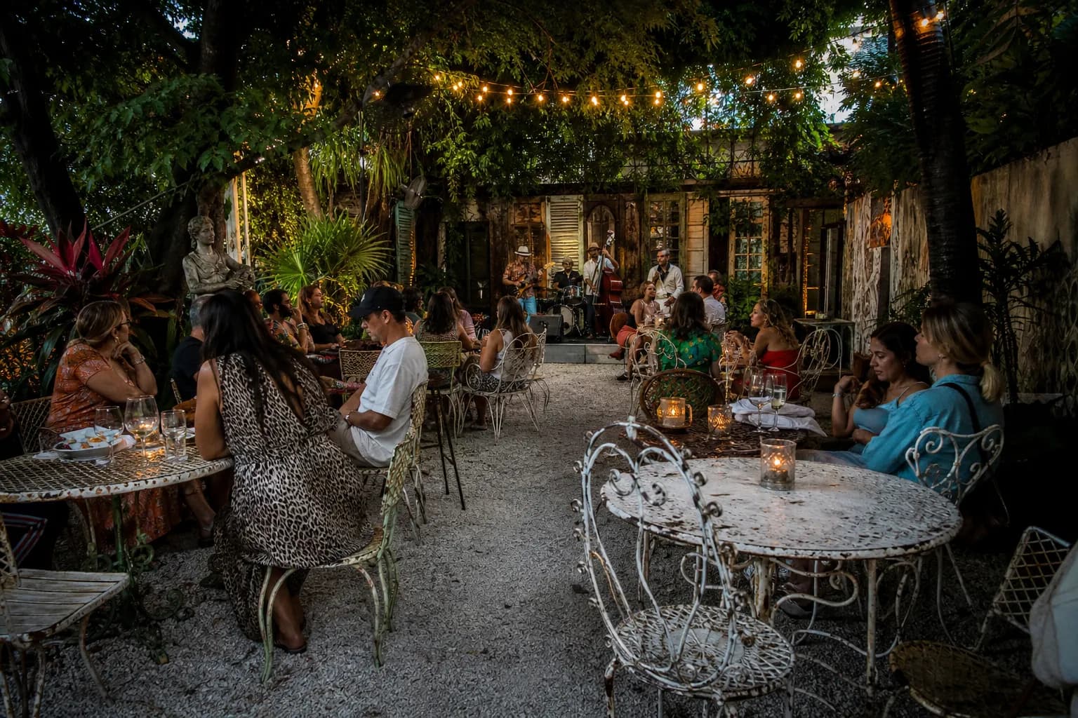 Cozy backyard garden at Lagniappe with string lights and people enjoying wine