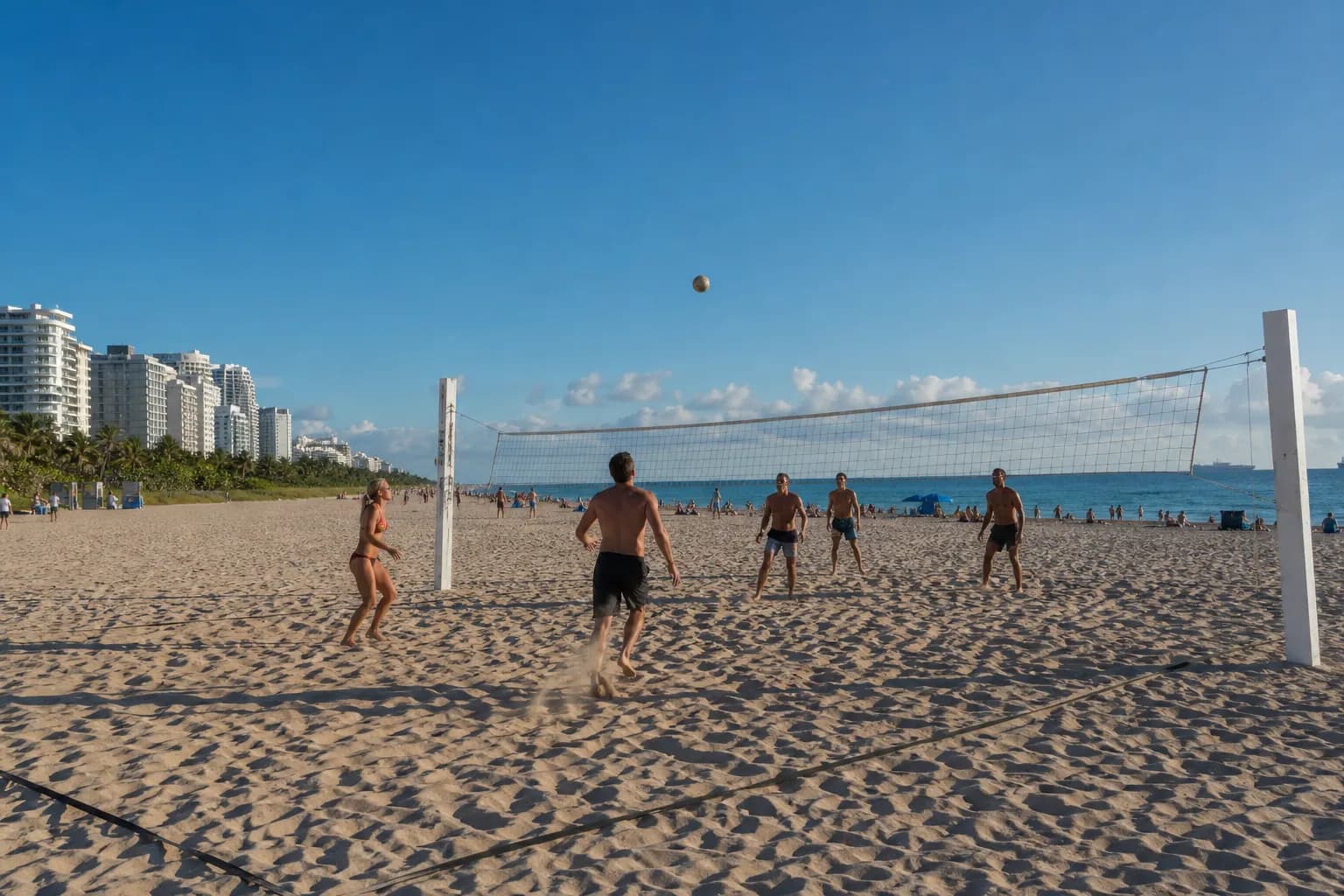Miami Beach volleyball courts with ocean, sand, and lifeguard towers in a wide public beach view