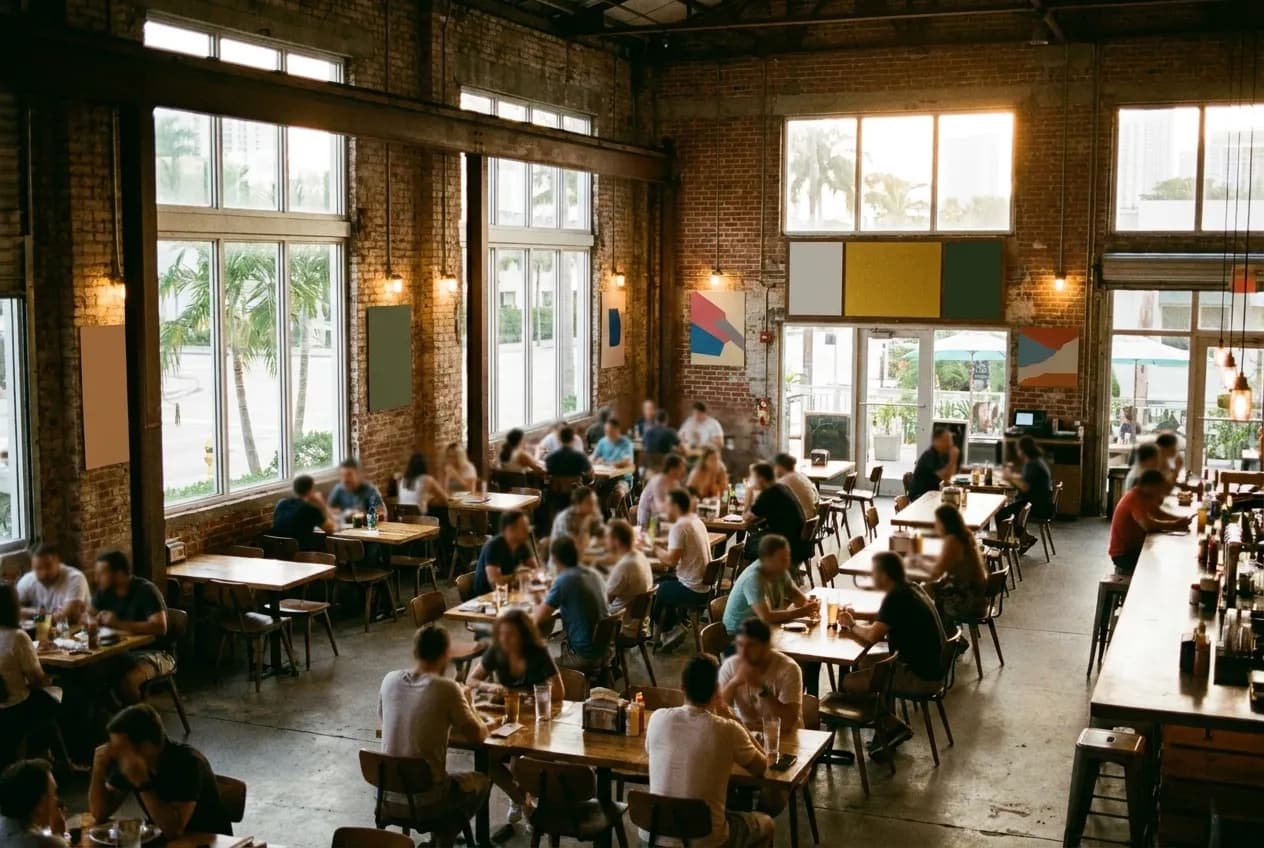 A converted warehouse dining room early in the evening, tables filling one at a time