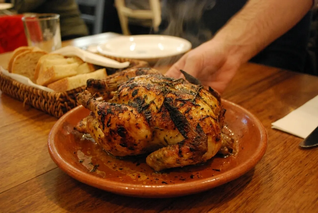 A wood-fired dish landing on the table, char still visible at the edges