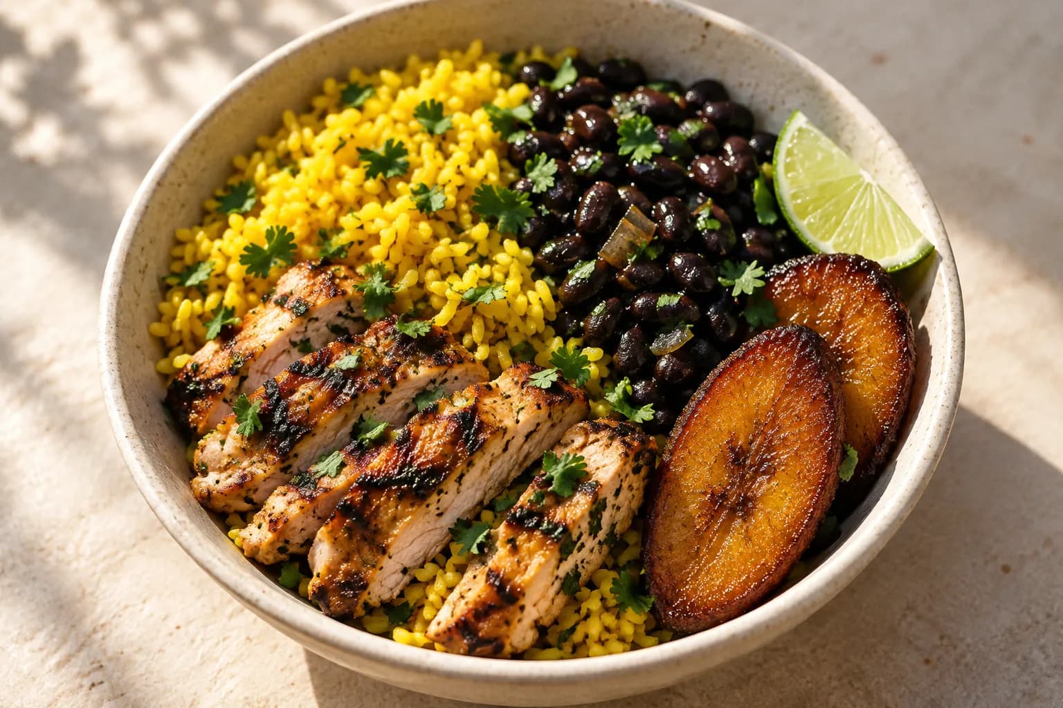 A bowl of yellow rice, black beans and grilled chicken with plantains