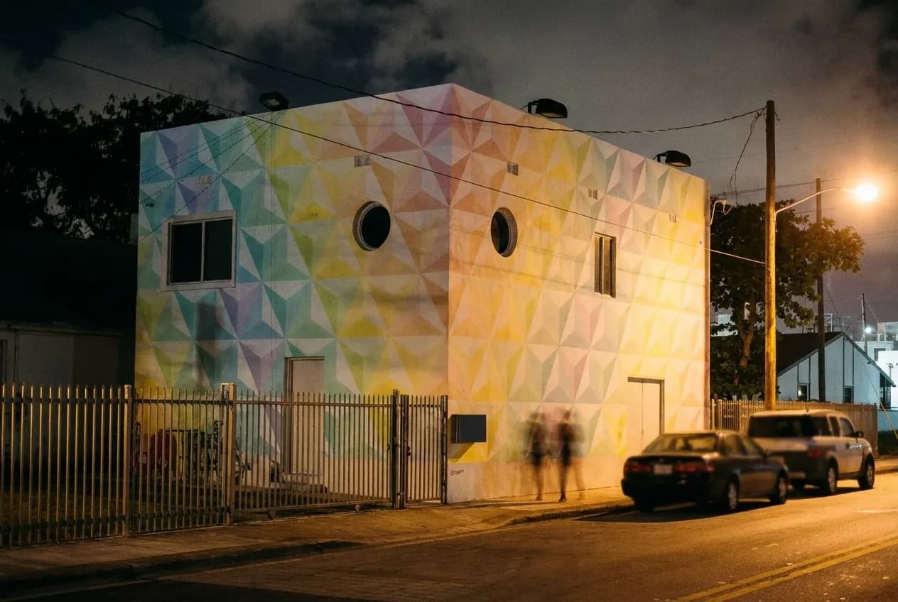 A low warehouse street at night, painted walls catching the street light